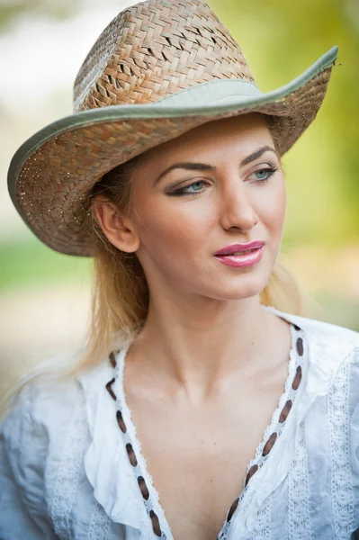 Attraente ragazza bionda con cappello di paglia e blouse.Beautiful bianco giovane donna con cappello di paglia e kaftan bianco outdoor.Gorgeous biondo capelli occhi blu mentre indossa un cappello di paglia cowboy . — Foto Stock