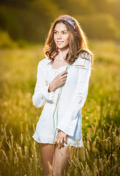 Menina com camisa branca no campo ao pôr-do-sol.Jovem mulher bonita de pé no campo de trigo .Vintage imagem de uma jovem mulher de pé em um campo de trigo .Sol no início do pôr-do-sol no fundo . — Fotografia de Stock