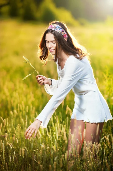 Ragazza con camicia bianca sul campo al tramonto.Giovane bella donna in piedi nel campo di frumento. Immagine dall'aspetto vintage di una giovane donna in piedi in un campo di frumento. Sole all'inizio del tramonto sullo sfondo . — Foto Stock