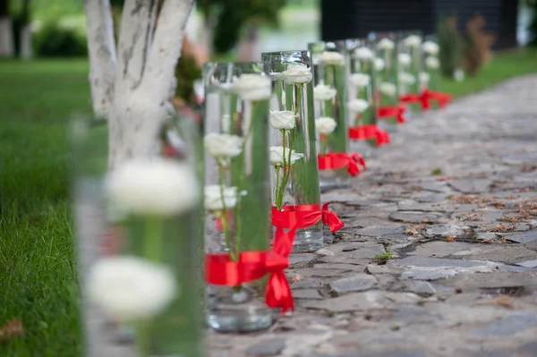 Roses in glass vases with red bow on alley — Stock Photo, Image