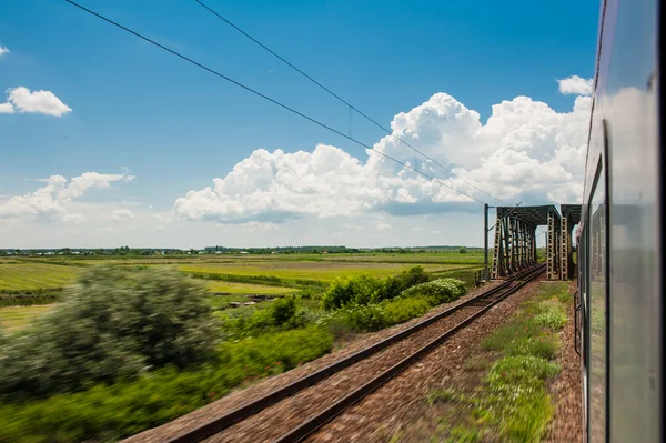 Railway goes to horizont in green and yellow landscape under blue sky with white clouds.railway under cloudy sky.Scenic railroad in rural area in summer and blue sky with white clouds. — Stock Photo, Image