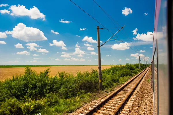 Railway goes to horizont in green and yellow landscape under blue sky with white clouds.railway under cloudy sky.Scenic railroad in rural area in summer and blue sky with white clouds. — Stock Photo, Image