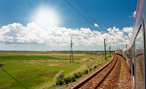 Σιδηρόδρομος πηγαίνει στο horizon στο πράσινο και κίτρινο τοπίο κάτω από μπλε ουρανό με λευκό clouds.railway υπό το θολό sky.scenic σιδηροδρόμου σε αγροτική περιοχή το καλοκαίρι και το γαλάζιο του ουρανού με τα λευκά σύννεφα. — Φωτογραφία Αρχείου