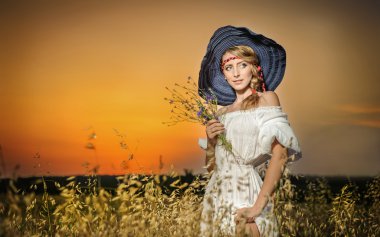 güneş doğarken sarı buğday alanı içinde beyaz outdoor.attractive Kadın kılığında field.romantic genç kadın kız background.portrait sunrise ile buğday alan üzerinde duran genç kadın.