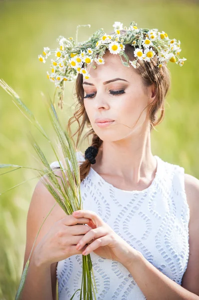 Mladá dívka s věncem na pšenice golden field.portrait krásná blondýnka s věncem divokých flowers.beautiful žena líbí daisy pole, hezká dívka relaxační venkovní, harmonie koncepce — Stock fotografie