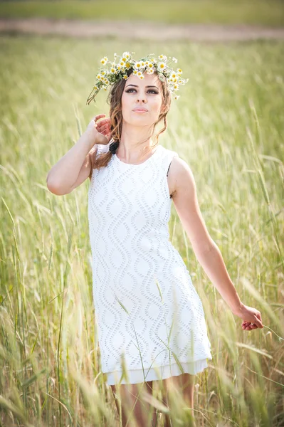 Young girl with wreath on golden wheat field.Portrait of beautiful blonde girl with wreath of wild flowers.Beautiful woman enjoying daisy field, pretty girl relaxing outdoor, harmony concept — Stock Photo, Image