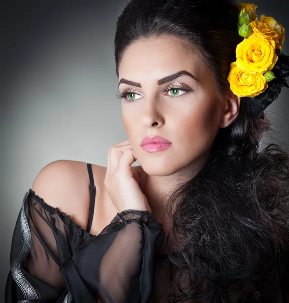 Peinado y maquillaje hermoso retrato de arte femenino con rosas amarillas. Elegancia. Genuina morena natural con flores. Retrato de una mujer atractiva con hermosos ojos y flores en el pelo . —  Fotos de Stock