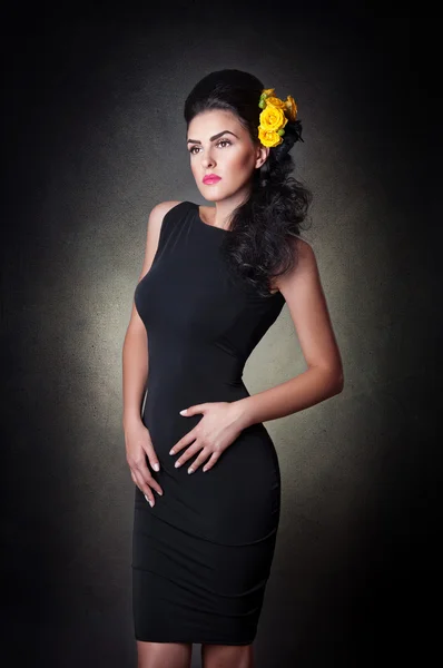 Attractive brunette woman in a black dress .Hairstyle - beautiful female art portrait with roses.Elegance. Genuine Natural girl with yellow roses. Portrait of a sexy woman with flowers in her hair. — Stock Photo, Image