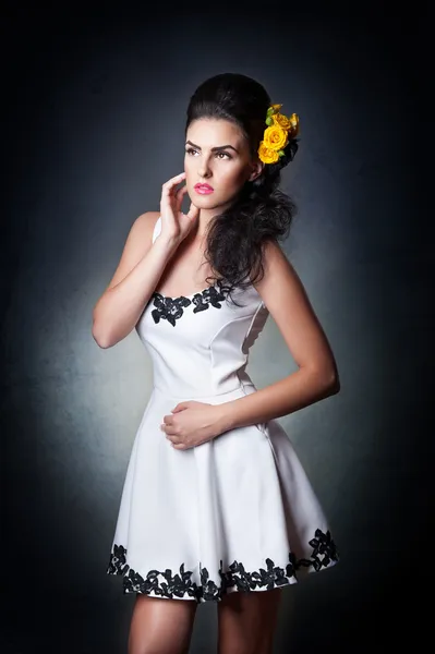 Aantrekkelijke brunette vrouw in een witte jurk .hairstyle - mooie vrouwelijke kunst portret met roses.elegance. echte natuurlijke meisje met gele rozen. Portret van een sexy vrouw met bloemen in haar haren. — Stockfoto