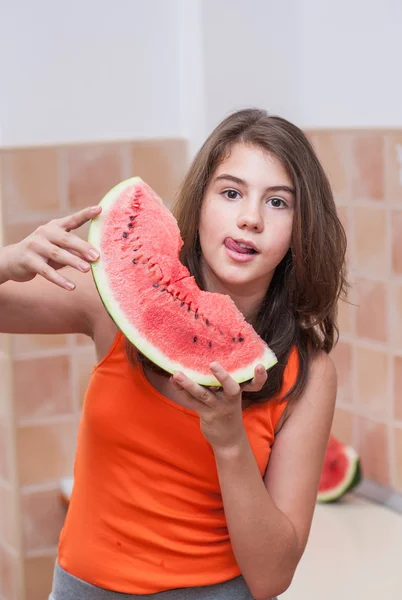 Beautiful teen girl with slice of fresh watermelon .Young girl eating watermelon.Portrait of teenage girl in red t-shirt and long hair holding watermelon slice in the chicken — Stock Photo, Image