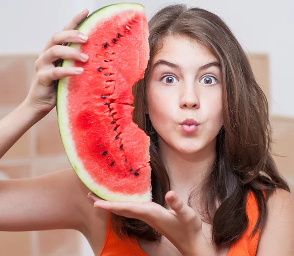 Hermosa chica adolescente con rebanada de sandía fresca. Chica joven comiendo sandía. Retrato de adolescente con camiseta roja y cabello largo sosteniendo rebanada de sandía en el pollo. — Foto de Stock