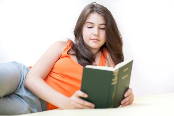 Pretty girl lying on the bed at home and reading a book. Teen lying in bed and reading. Young woman reading book in bed — Stock Photo, Image