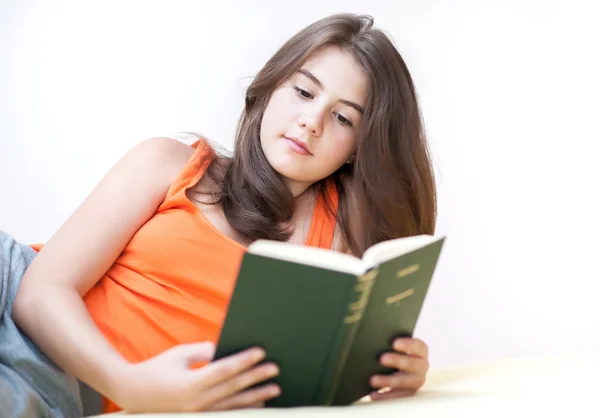 Pretty girl lying on the bed at home and reading a book. Teen lying in bed and reading. Young woman reading book in bed — Stock Photo, Image