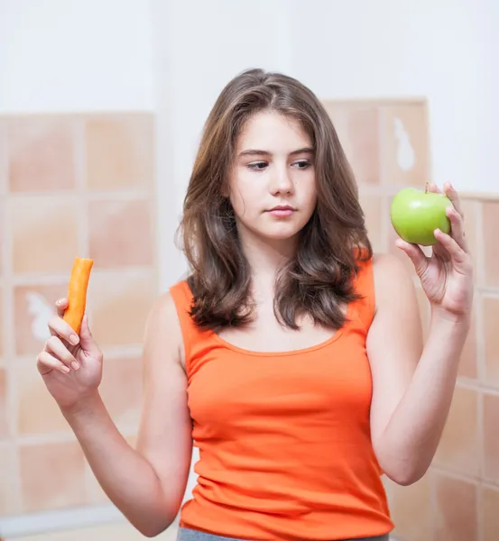 Teen girl holding a beautiful fresh green apple and a peach. Pretty teen girl concentrated hold green fresh apple and a peach in her hands. girl holding an green apple and a peach, healthy eating — Stock Photo, Image