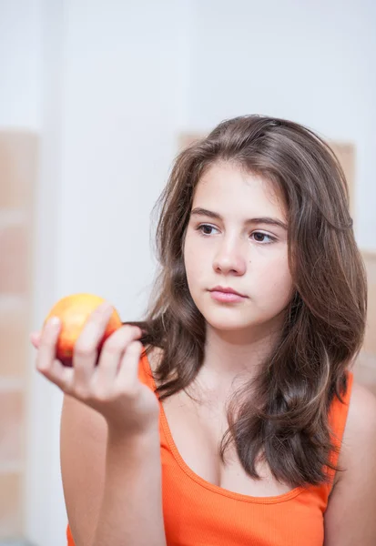 Pretty teen girl eating a peach, indoor.Beautiful teenage girl biting a peach .Picture of beautiful teenage biting a peach — Stock Photo, Image