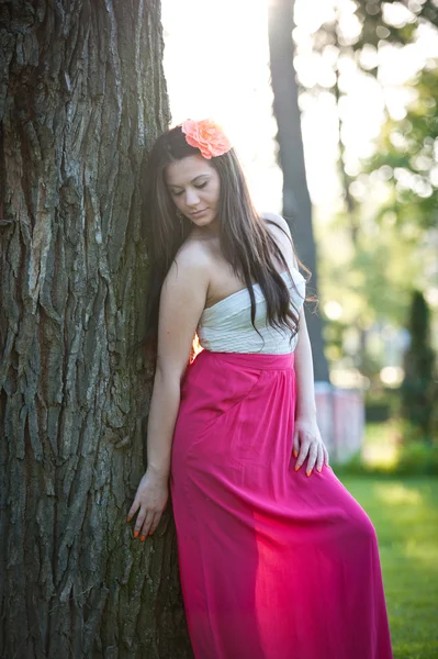 Longitud completa de la joven mujer caucásica con falda larga roja de pie cerca del árbol al aire libre.Retrato romántico de la mujer en el bosque —  Fotos de Stock