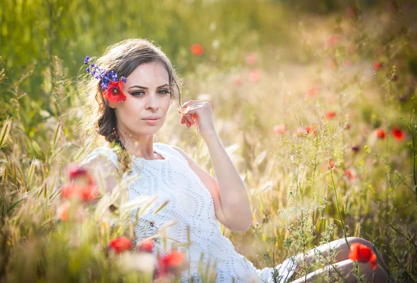 Jovem no campo de trigo dourado.Retrato de menina loira bonita com coroa de flores silvestres.Mulher bonita desfrutando de campo de margarida, menina bonita relaxante ao ar livre, conceito de harmonia — Fotografia de Stock