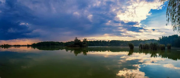 Apus de soare cu cer dramatic deasupra lacului. Râul de toamnă cu cer înnorat la apus. Frumos apus de soare și nori romantici pe cer peste un lac — Fotografie, imagine de stoc