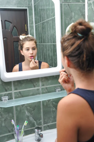 Una hermosa adolescente poniendo lápiz labial y comprobando como se ve. Adolescente chica feliz con su apariencia en el espejo usando lápiz labial . —  Fotos de Stock