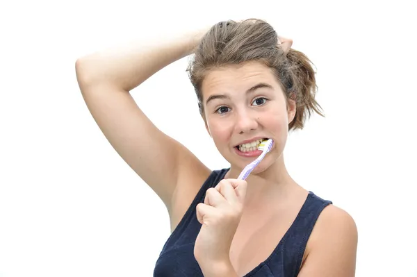 Портрет улыбающегося подростка, чистящего зубы на белом фоне. Красивая девочка-подросток держит длинные волосы рукой и чистит зубы, улыбаясь . — стоковое фото