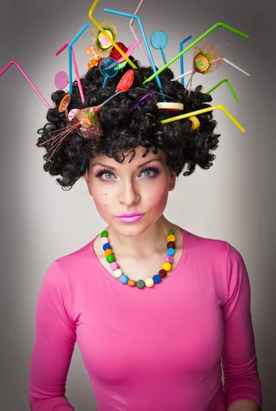 Retrato de um belo modelo feminino no fundo branco com pirulitos no cabelo.Menina glamourosa com blusa rosa vestindo pirulito e palha colorida no cabelo — Fotografia de Stock