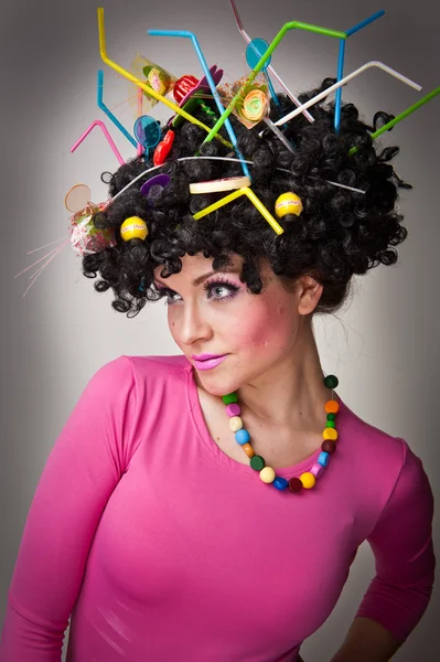 Portrait of a beautiful female model on white background with lollipops in the hair.Glamorous girl with pink blouse wearing lollipop and straw colored in hair — Stock Photo, Image