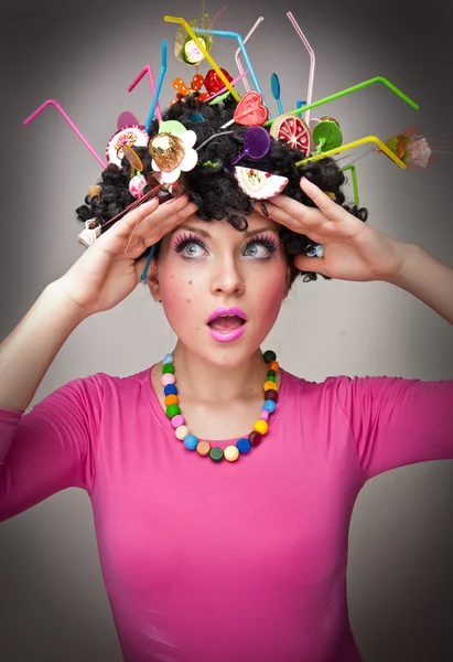 Portrait of a beautiful female model on white background with lollipops in the hair.Glamorous girl with pink blouse wearing lollipop and straw colored in hair — Stock Photo, Image