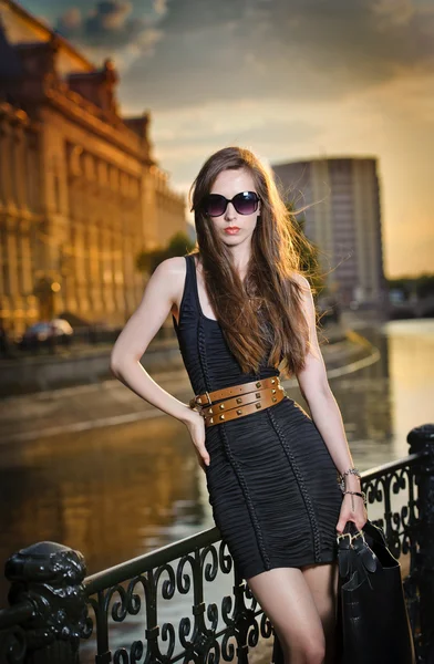Mode-model op de straat met zonnebril en korte zwarte dress.fashionable meisje met lange benen die zich voordeed op street.high mode stedelijke portret van jong, slim, mooi model — Stockfoto