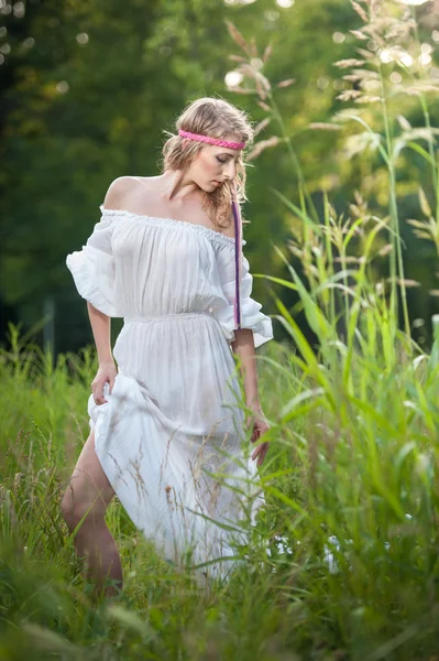 Retrato de uma jovem mulher loira sensual em campo em vestido longo branco sexy. Retrato de bela menina loira ao ar livre. Mulher bonita desfrutando de campo verde, menina bonita relaxante ao ar livre — Fotografia de Stock