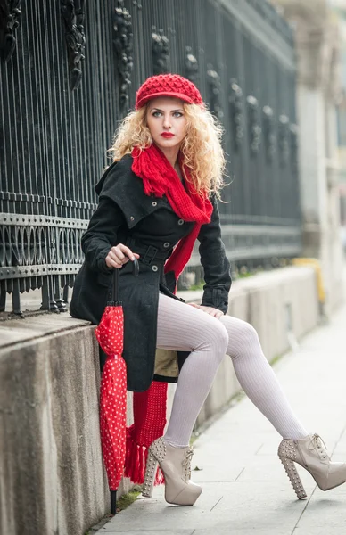 Ελκυστική νεαρή γυναίκα σε μια μόδα χειμώνα που πυροβολήθηκε. όμορφη μόδας νεαρή κοπέλα με την κόκκινη ομπρέλα στο δρόμο — Φωτογραφία Αρχείου