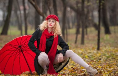sonbahar moda çekimi çekici genç kadın. Kırmızı şemsiye, kırmızı şapka ve kırmızı eşarp parkta güzel şık genç kız. Kırmızı Aksesuar açık poz ile sarışın kadın