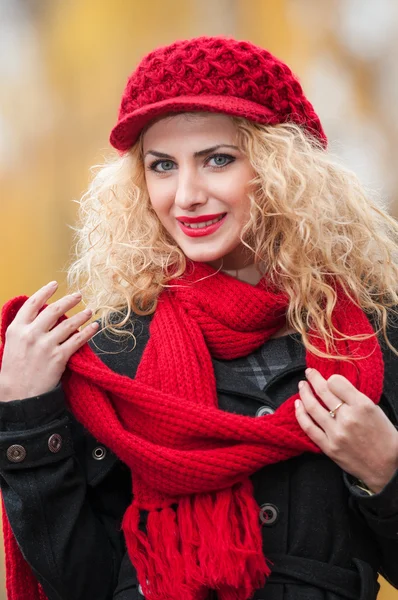 Attraente giovane donna in un servizio fotografico di moda autunno. Bella ragazza alla moda con berretto rosso e sciarpa rossa nel parco. Donne bionde con accessori rossi in posa all'aperto. Bella ragazza dai capelli biondi — Foto Stock