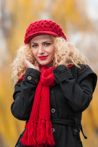 Jovem atraente em uma sessão de moda de outono. Menina bonita e elegante com boné vermelho e cachecol vermelho no parque. Mulheres loiras com acessórios vermelhos posando ao ar livre. Menina de cabelo claro agradável — Fotografia de Stock