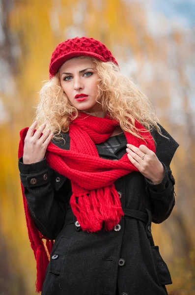 Attrayant jeune femme dans un tournage de mode d'automne. Belle jeune fille à la mode avec casquette rouge et écharpe rouge dans le parc. Femmes blondes avec des accessoires rouges posant en plein air. Belle fille aux cheveux blonds — Photo