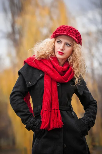 Attrayant jeune femme dans un tournage de mode d'automne. Belle jeune fille à la mode avec casquette rouge et écharpe rouge dans le parc. Femmes blondes avec des accessoires rouges posant en plein air. Belle fille aux cheveux blonds — Photo