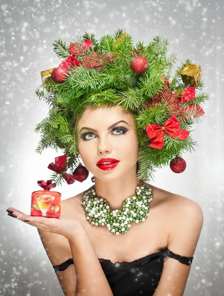 Hermoso maquillaje creativo de Navidad y el estilo de pelo de la sesión de interior. Chica modelo de moda de belleza. El invierno. Hermosa chica atractiva con accesorios de árbol de Navidad en el estudio sosteniendo un regalo . — Foto de Stock