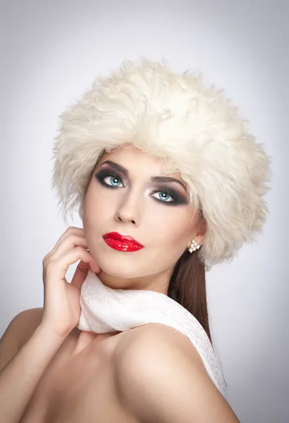 Привлекательный молодой кавказский взрослый человек с белым шарфом на сером фоне. Красивая девушка с красными губами в белой меховой шляпе - студия изолирована. Макияж - красивая студия женского художественного портрета — стоковое фото