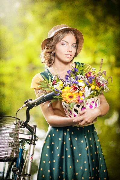 Piękna dziewczyna z ładny kapelusz i kosz z kwiatami, zabawy w parku z rowerów. koncepcja zdrowy zewnątrz życia. sztuka dekoracje. ładny blond dziewczyna dzięki wyglądowi retro z roweru Obrazek Stockowy