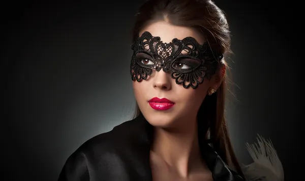 Ritratto di attraente giovane donna sensuale con maschera. Giovane signora bruna attraente in posa su sfondo scuro in studio. Ritratto della bella donna sexy di moda con labbra rosse e maschera interna — Foto Stock