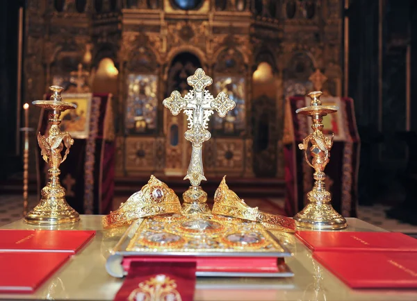 Croix, anneaux et couronnes d'or sur la table de l'église. Fête de mariage — Photo