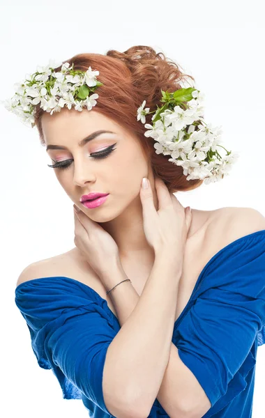 Retrato de una hermosa chica en el estudio con flores de primavera en el pelo. Mujer joven atractiva en azul con flores blancas brillantes. Peinado creativo y maquillaje, foto de moda estudio de tiro —  Fotos de Stock