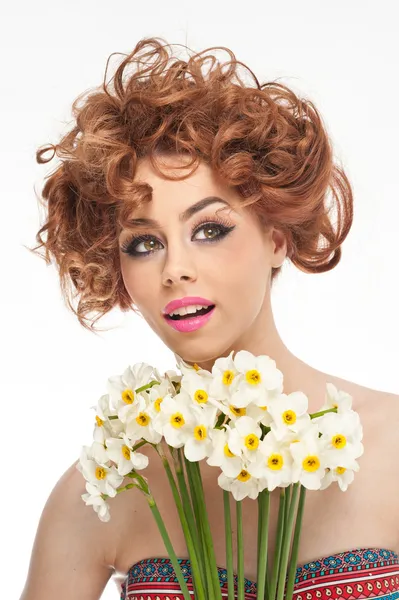 Portrait de belle fille bouclée en studio avec jonquilles. Sexy jeune femme avec de beaux yeux bleus avec des fleurs blanches brillantes. Coiffure créative et maquillage, photo studio de mode prise — Photo