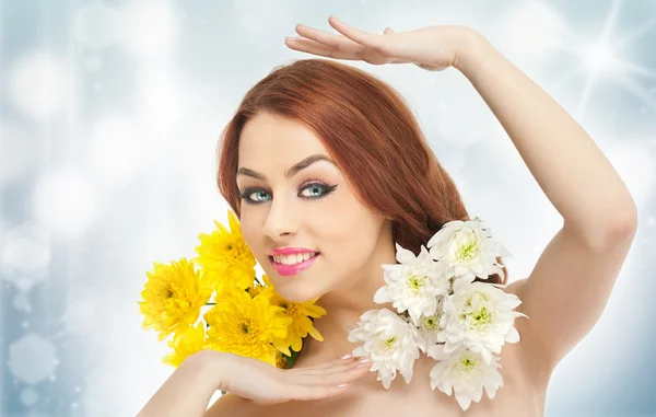 Portrait of beautiful girl in studio with yellow and white chrysanthemums in her hair. Sexy young woman with blue eyes and bright flowers. Creative hairstyle and makeup, fashion photo studio shot — Stock Photo, Image