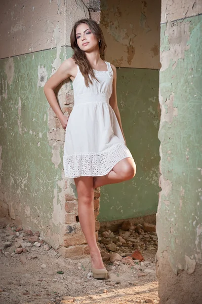 Beautiful girl posing fashion near an old wall. Pretty young woman posing laying on a wall. Very attractive blonde girl with a transparent white short dress. Romantic young woman posing — Stock Photo, Image