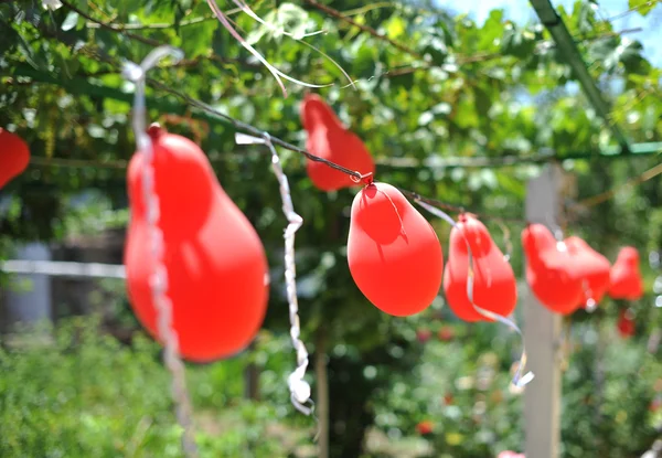 Rode ballonnen buiten vliegen. ballonnen opknoping in een zomertuin. bruiloft decoratie met rode ballonnen. — Stockfoto