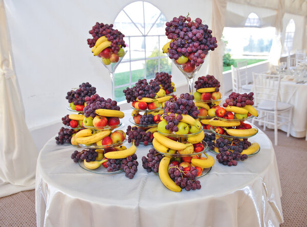 Fruits arrangement on restaurant table. Wedding decoration with fruits, bananas, grapes and apples.