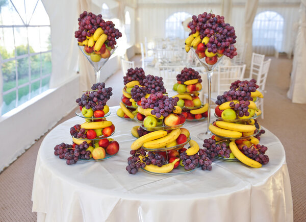 Fruits arrangement on restaurant table. Wedding decoration with fruits, bananas, grapes and apples.