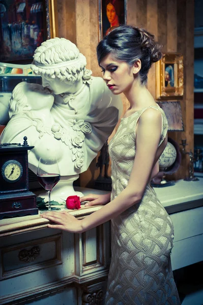 Belle femme sexy en dentelle blanche robe dans des paysages vintage. Portrait de jeune brune à la coupe de cheveux créative posant dans un intérieur de luxe près d'une statuaire. Attrayant élégant femelle à la mode avec rose — Photo