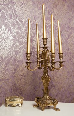 lüks dokulu duvar önünde beyaz masa beş mum ile altın şamdan. Vintage Mumluk, mumlar ve altın ile duvar kağıdı arka plan olarak tabloda köşeli