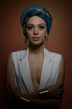 Sarık güzel kadın. Genç güzel kadın Türban ve altın aksesuarlar ile. Güzellik modaya uygun kadın Türban içinde sarılı tüyleri ile. Çok beyaz modeli Studio poz küpeler.